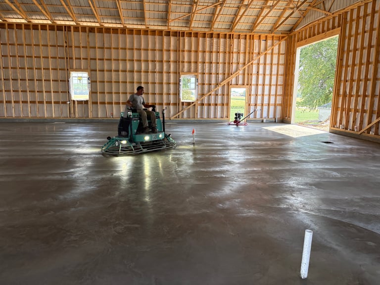Worker operating a polishing machine on concrete floor inside a new wooden warehouse building