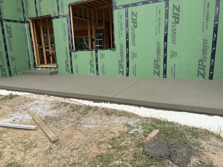 Concrete foundation with green house wrap and window frames during home construction or renovation