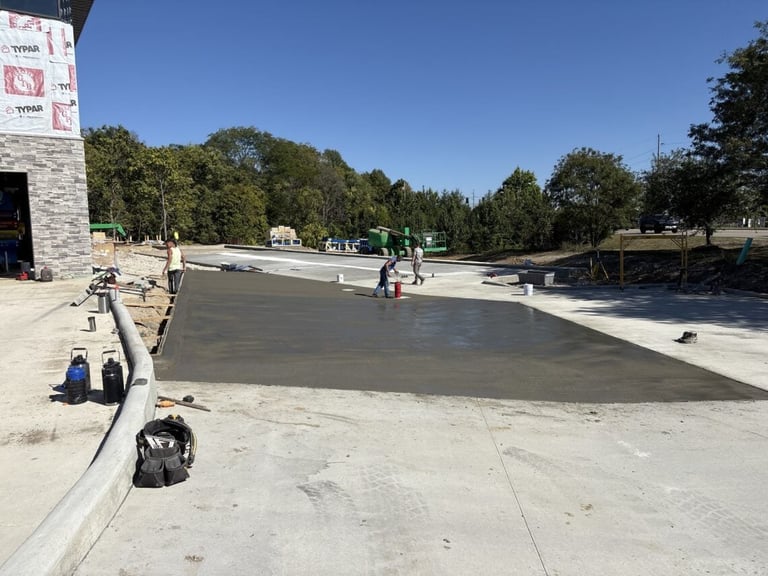Construction workers applying concrete coating to a large outdoor pool or skating rink surface on a sunny day