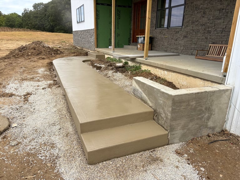 Concrete entrance platform with steps leading to a modern residential building with green doors and brick exterior