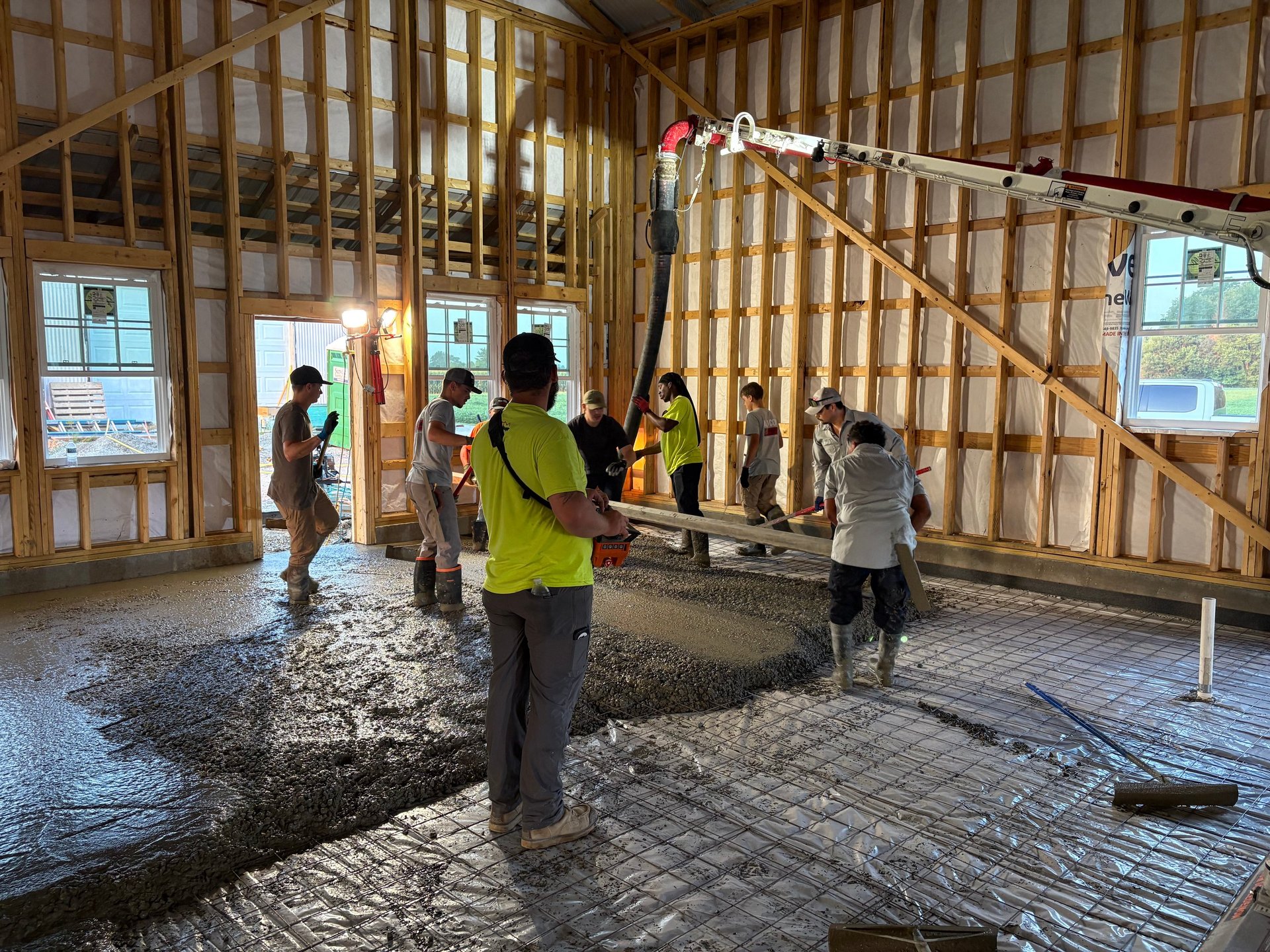 Construction workers in safety vests and helmets working inside a wooden-framed building under construction